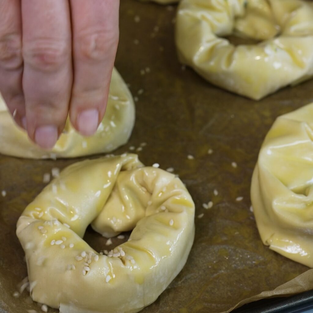 Sprinkling sesame seeds over the shaped filo doughnuts