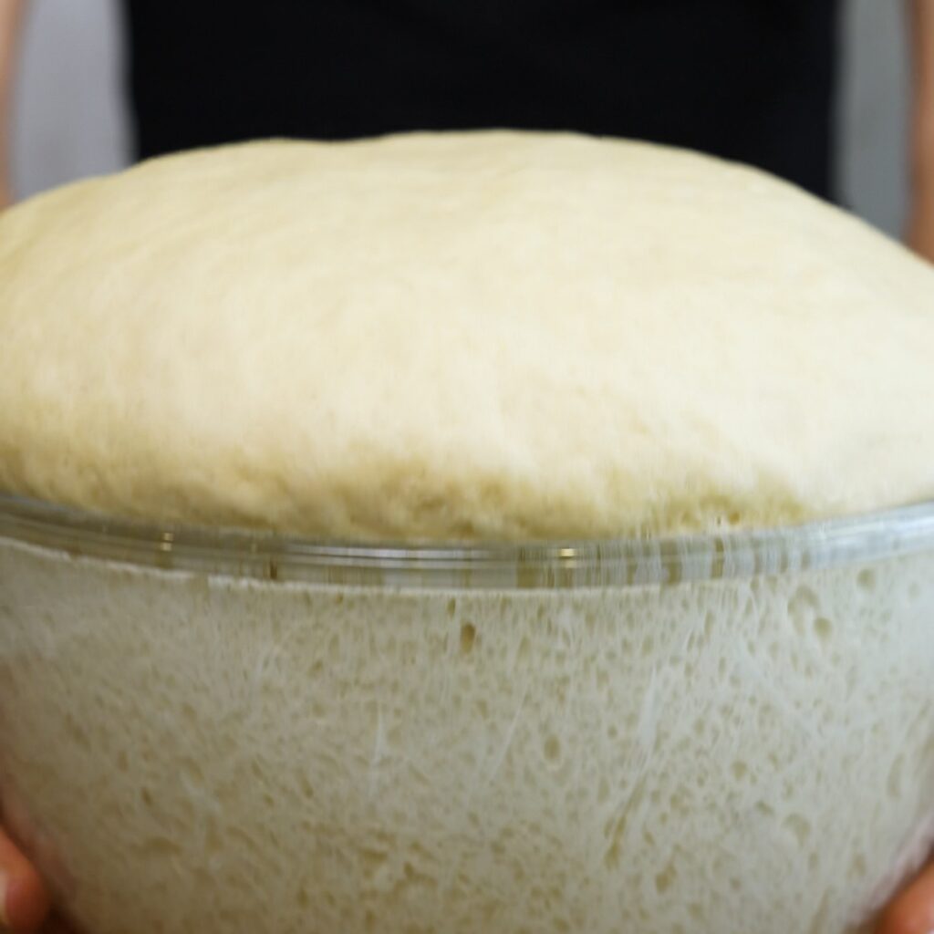 Risen blueberry roll dough in a lightly oiled bowl
