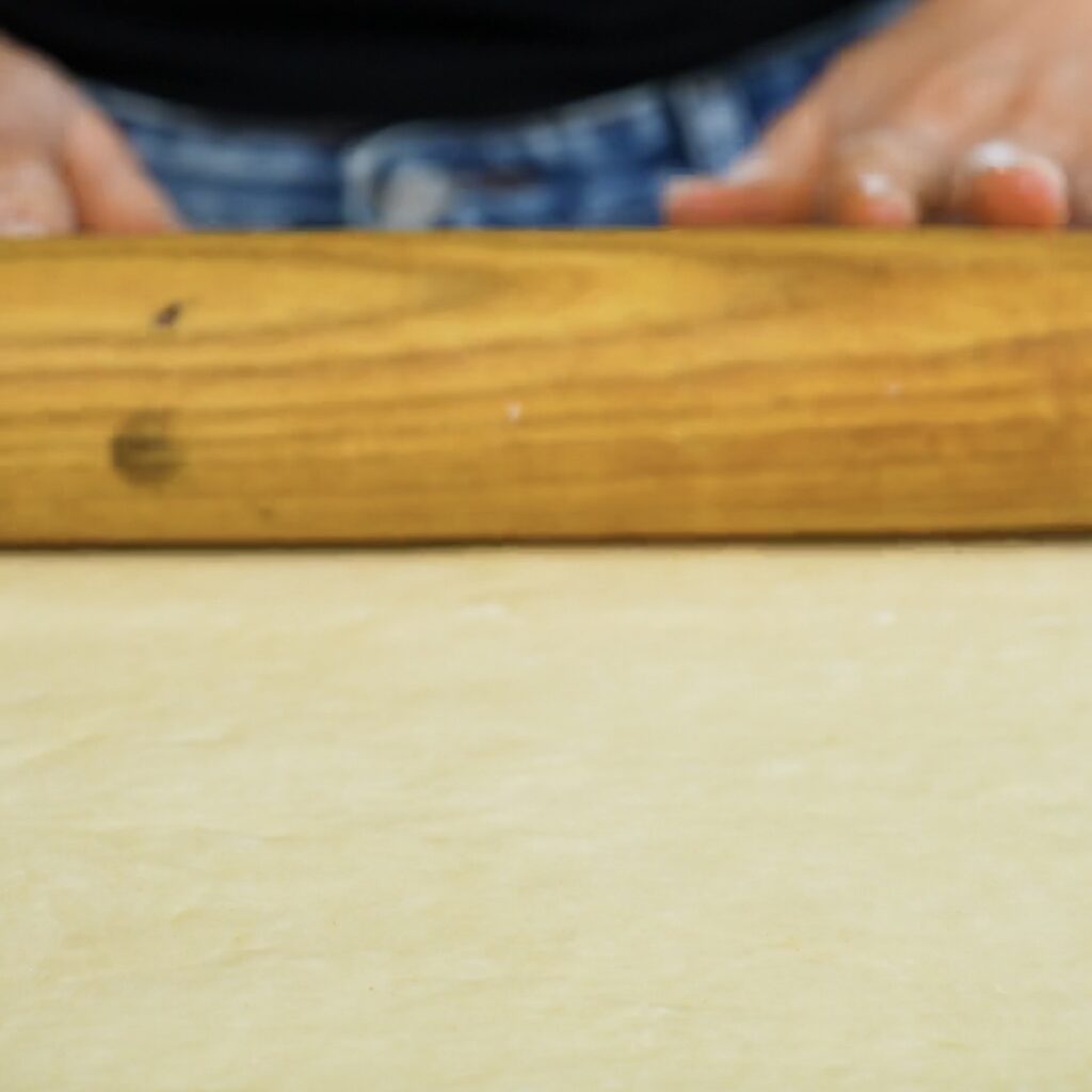 Rolling blueberry roll dough into a rectangle