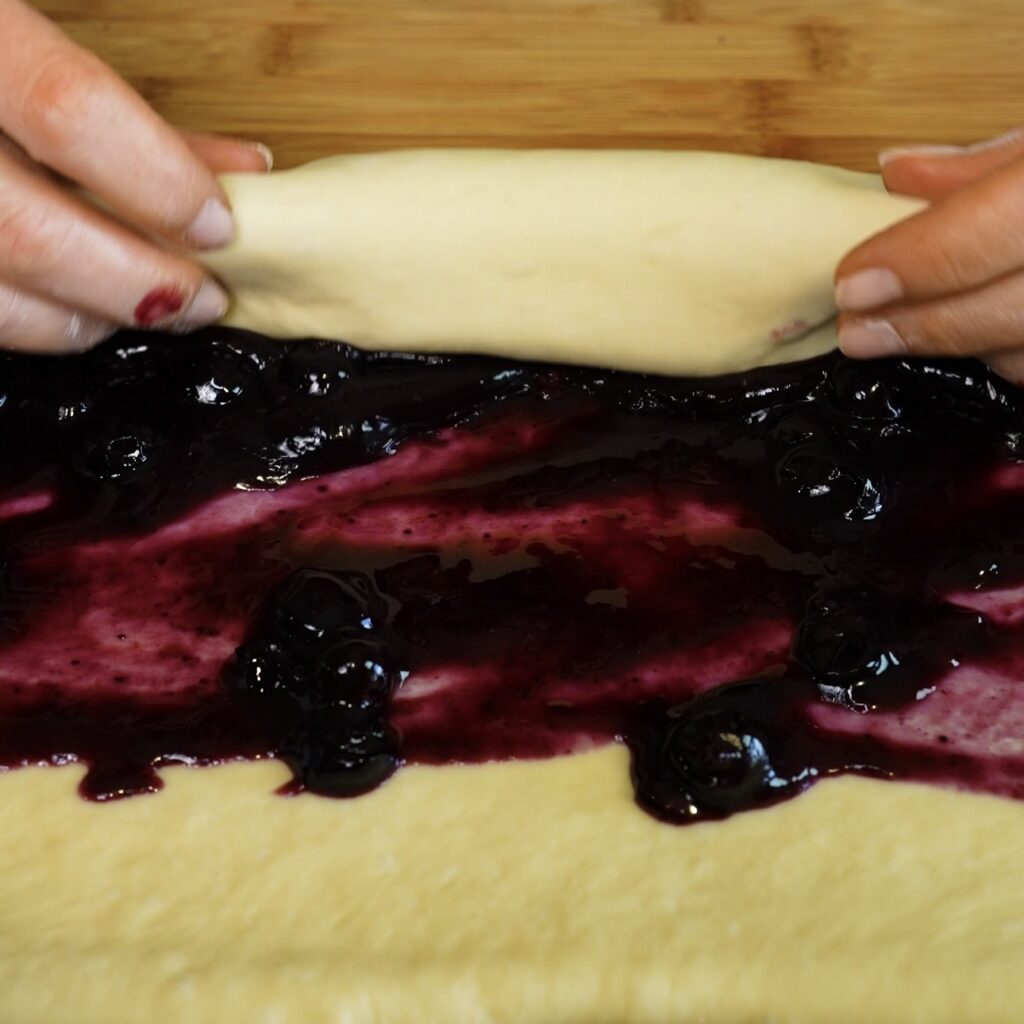 Rolling blueberry-filled dough into a log