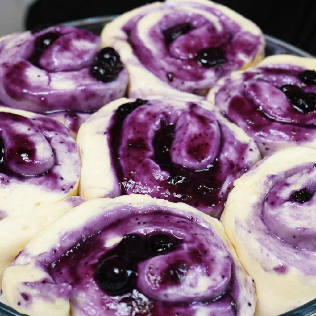 Risen blueberry rolls in a baking dish