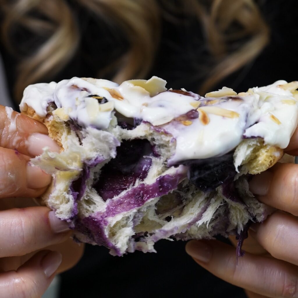 Hands pulling apart a soft blueberry roll