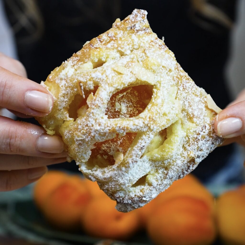Hands holding a freshly baked Apricot Mascarpone Puff.
