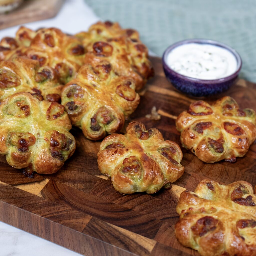Pesto Mozzarella Puffs served on a wooden board with a garlic yogurt sauce