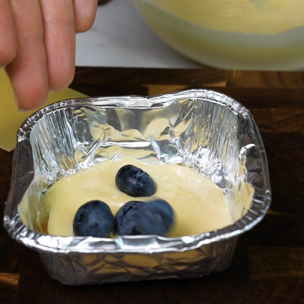 Adding another layer of ricotta cream and fresh blueberries over the lasagna sheet.