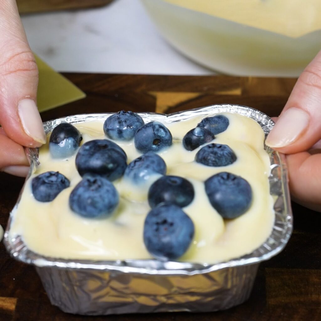 Assembled Blueberry Ricotta Lasagna topped with ricotta cream and blueberries, ready for baking.