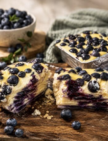 Blueberry Ricotta Lasagna served on a wooden board, sliced in half to show the creamy ricotta, blueberry and pasta layers.