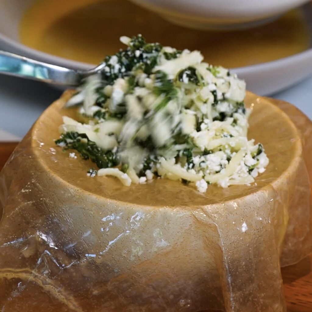 Spinach, feta and mozzarella filling being added to the centre of a rice paper sheet.