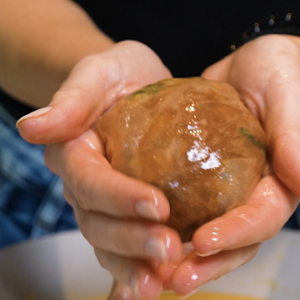 Spinach Feta Rice Paper Bomb being shaped into its final round form after double wrapping.