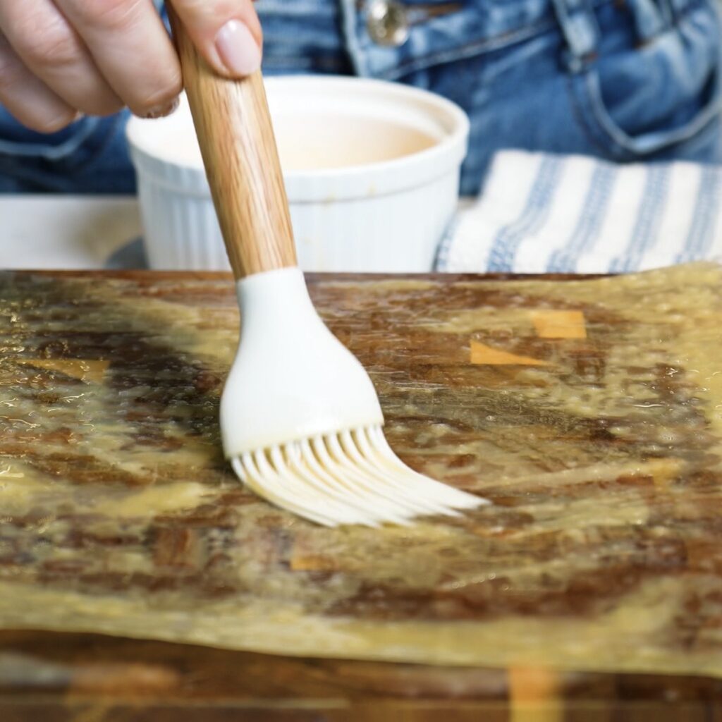 Brushing rice paper with egg wash while preparing Crispy Rice Paper Toast.