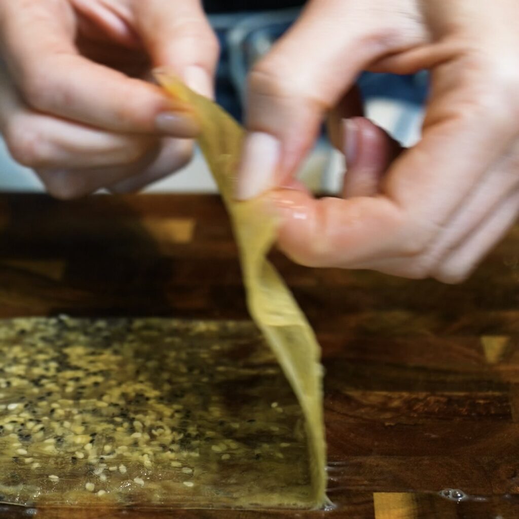 Folding egg-washed rice paper into a smaller layered square for Crispy Rice Paper Toast.