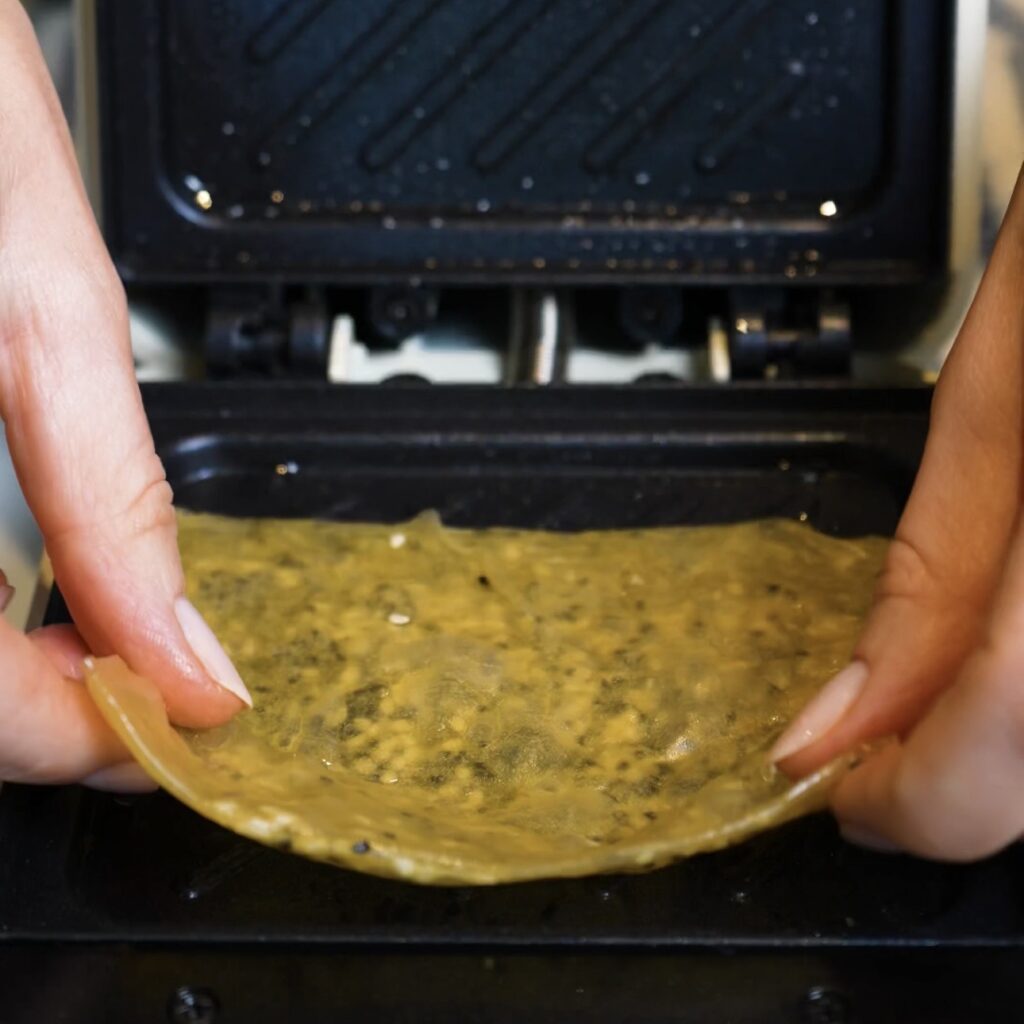 Placing folded rice paper into a sandwich maker for Crispy Rice Paper Toast.