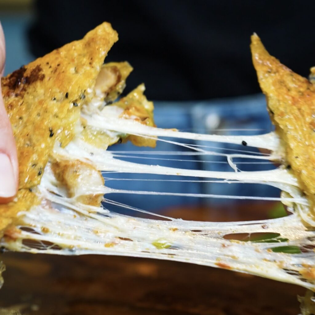 Cheese pull from Crispy Rice Paper Toast filled with chicken, pesto and melted mozzarella.