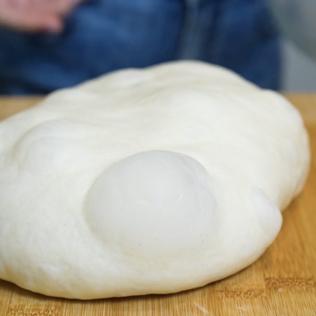 Risen homemade flatbread dough in a bowl after proofing until light and airy.