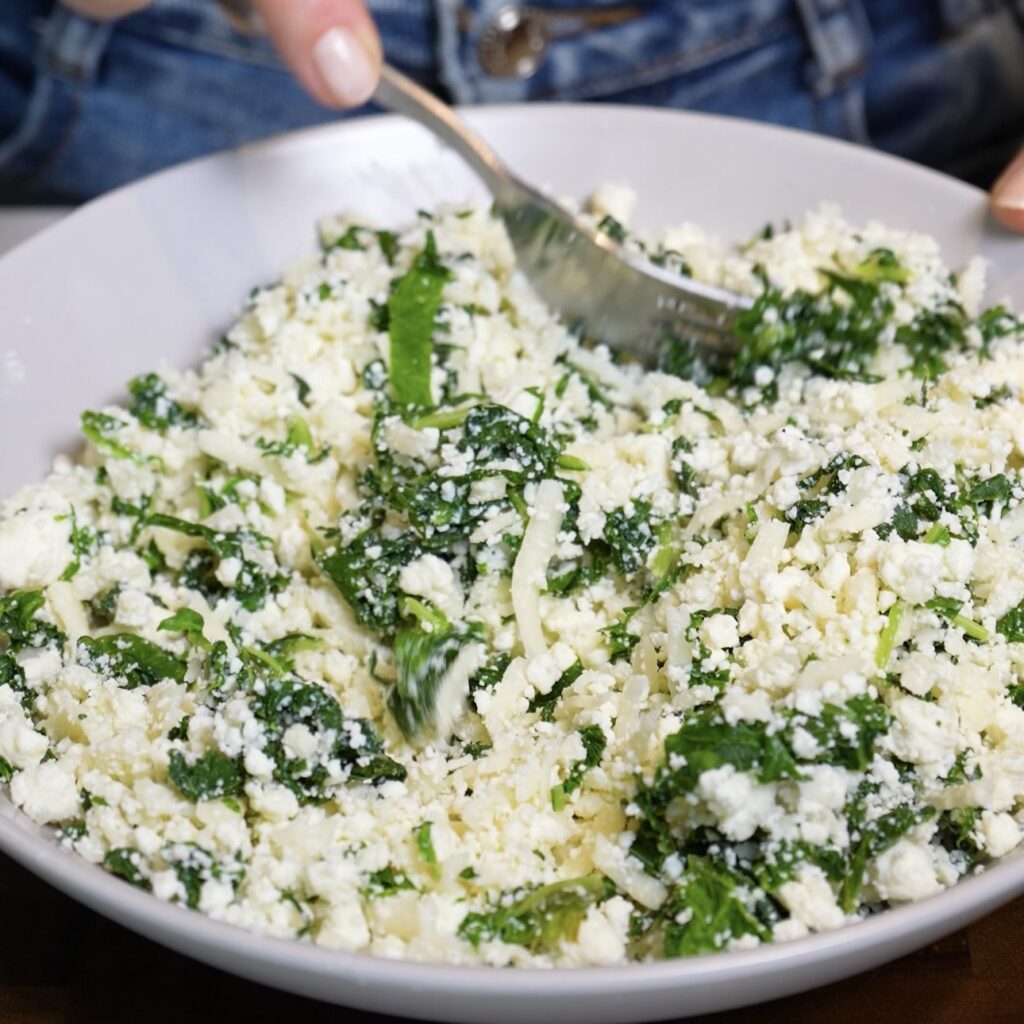 Spinach, feta and mozzarella being mixed together in a bowl for the flatbread filling
