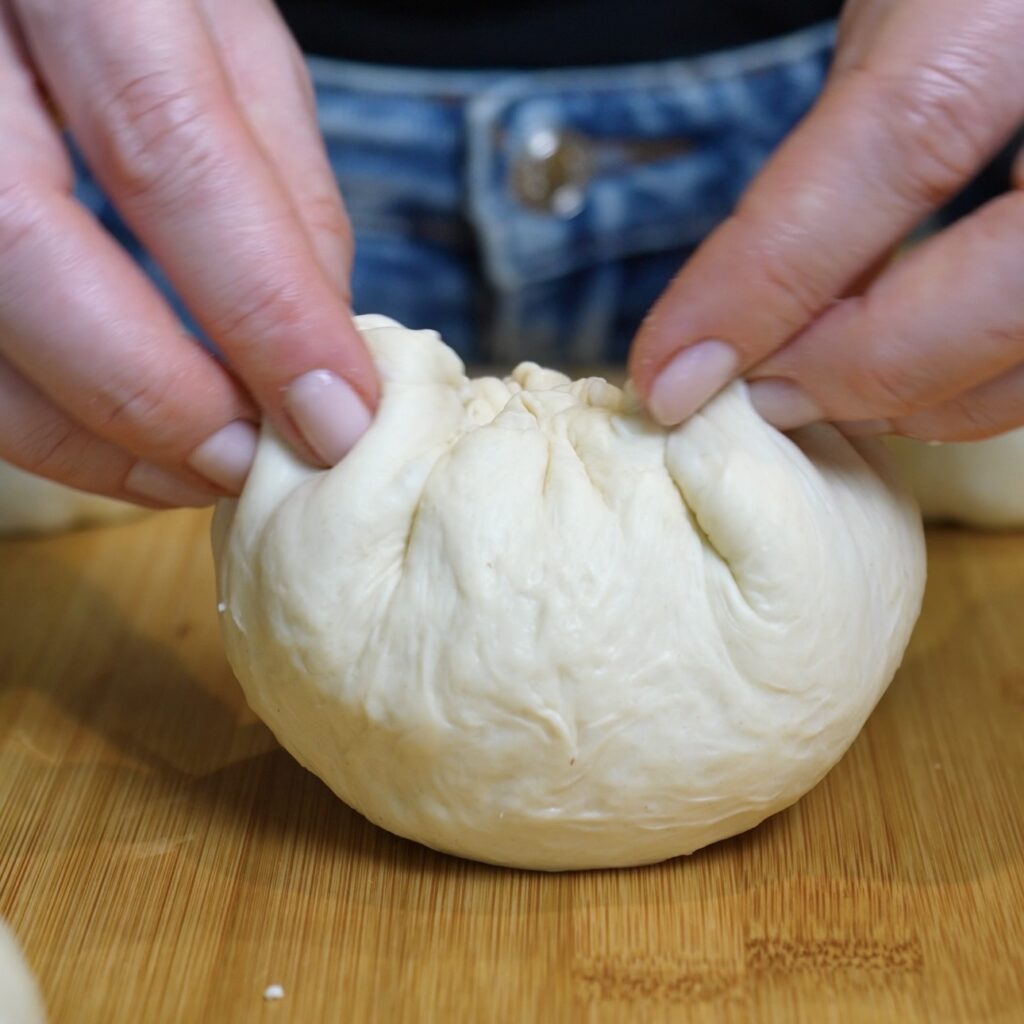 Flatbread dough being sealed around the filling and shaped into a ball