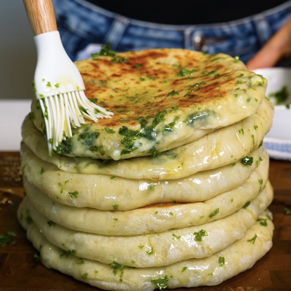 Cooked Spinach and Feta Flatbreads being brushed with olive oil and fresh parsley.