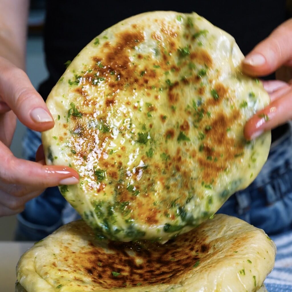 Hands holding a freshly cooked Spinach and Feta Flatbread ready to serve.