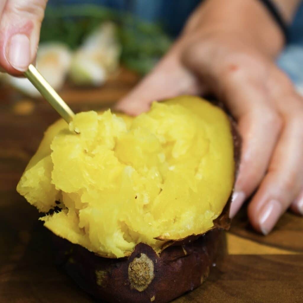 Scooping the soft cooked flesh from a Japanese sweet potato for homemade sweet potato gnocchi