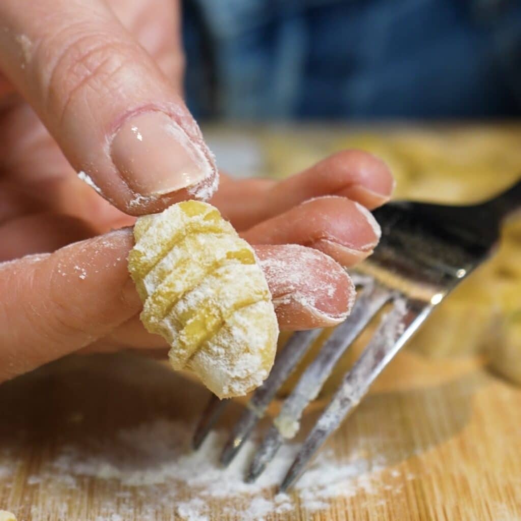 Shaping sweet potato gnocchi with a fork to create classic ridges