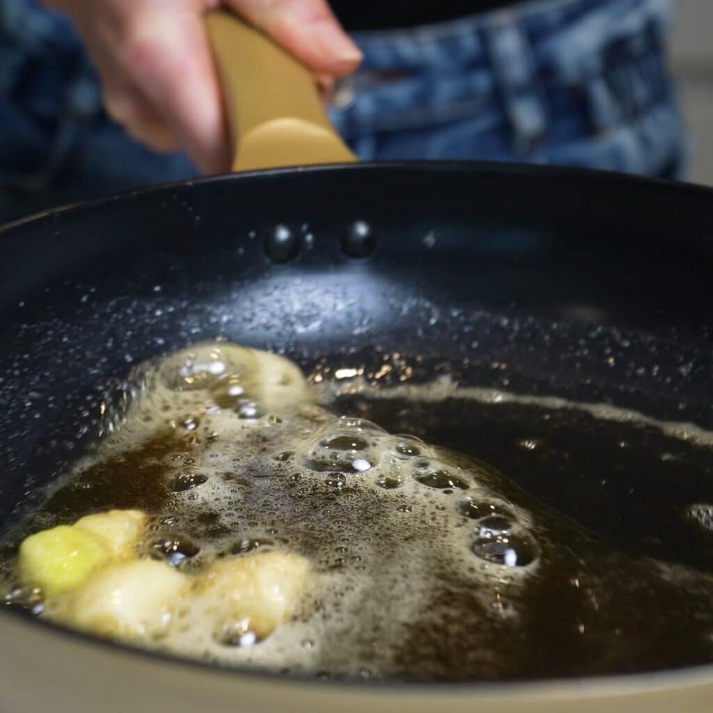 Butter and crushed garlic cooking in a frying pan for sweet potato gnocchi