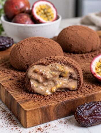 High-Protein Chocolate Rice Paper Mochi served on a wooden board with one cut in half to reveal the passion fruit centre