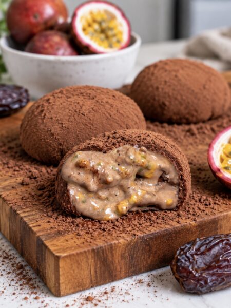 High-Protein Chocolate Rice Paper Mochi served on a wooden board with one cut in half to reveal the passion fruit centre