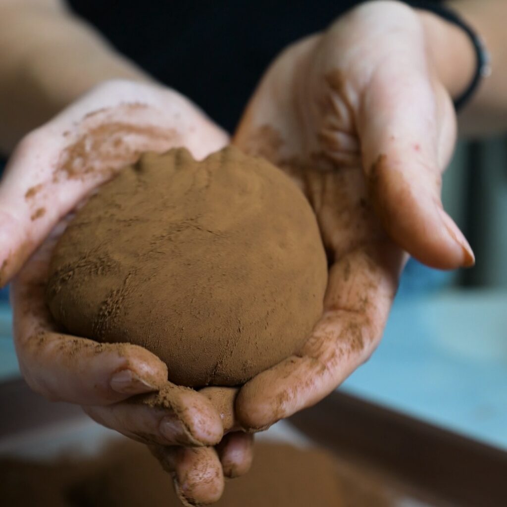 Hands holding one chocolate rice paper mochi dusted with cocoa powder.