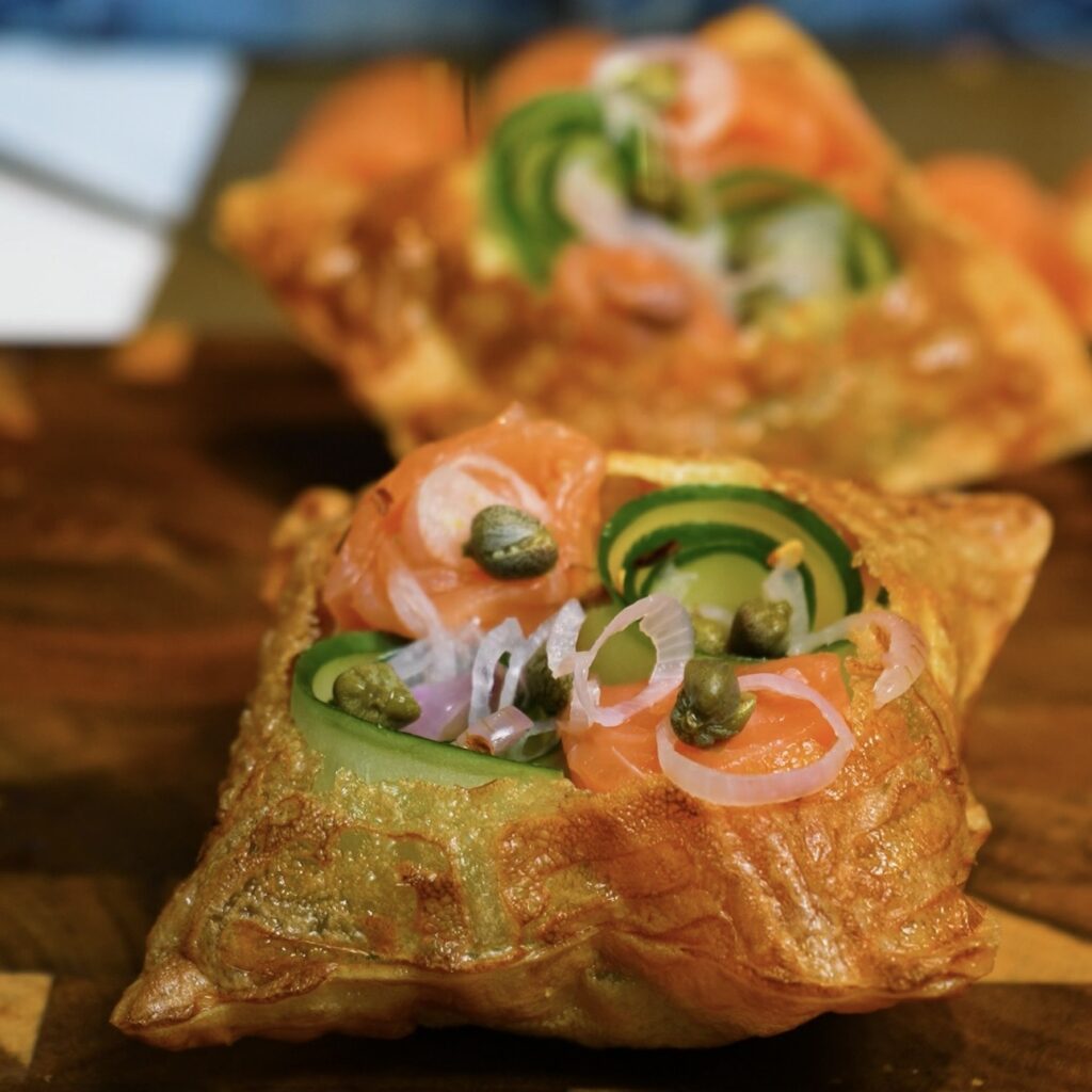 Sprinkling chilli flakes over smoked salmon and avocado rice paper tarts.