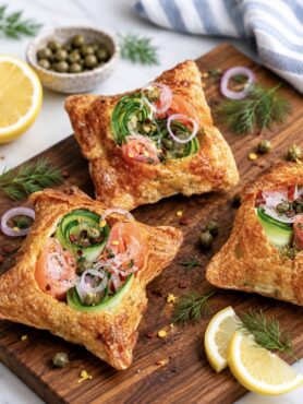 Crispy rice paper tarts with smoked salmon and avocado served on a wooden board.