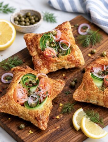 Crispy rice paper tarts with smoked salmon and avocado served on a wooden board.