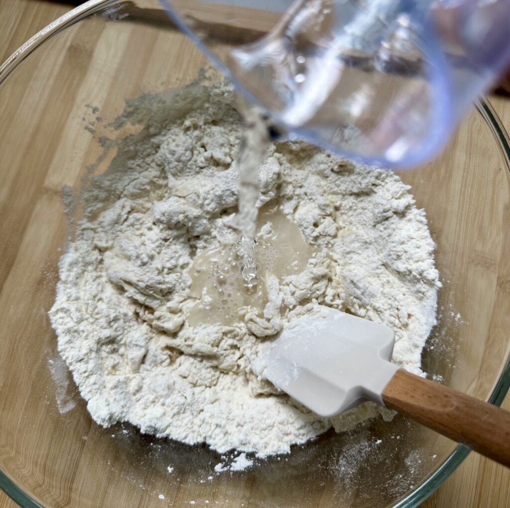 Adding water to flour for Azerbaijani Qutab dough