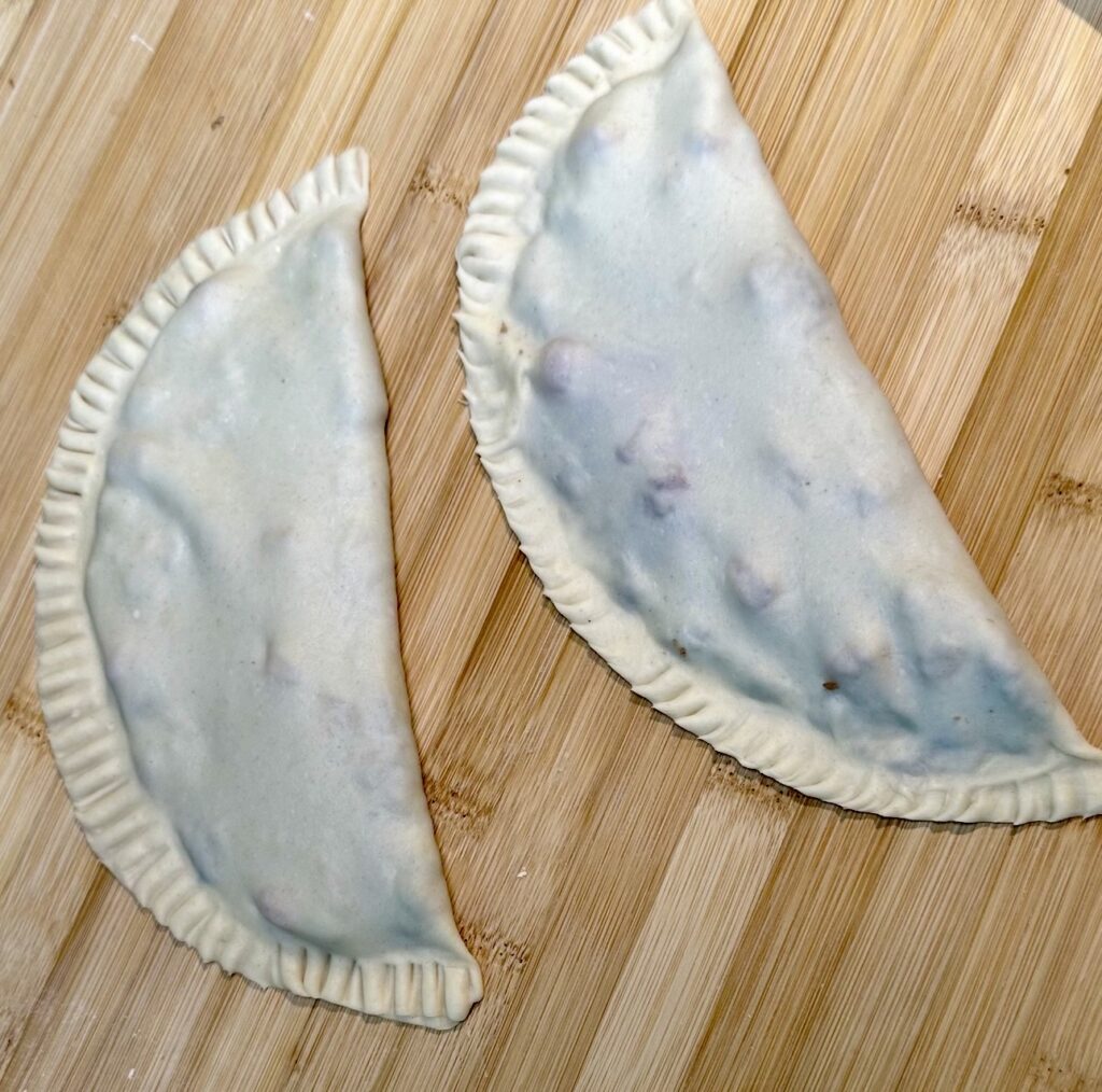 Two uncooked Azerbaijani Qutab flatbreads on a wooden board