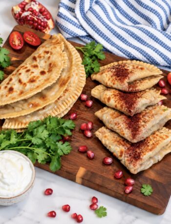 Meat-Stuffed Flatbread (Azerbaijani Qutab) served on a wooden board with sumac and yoghurt