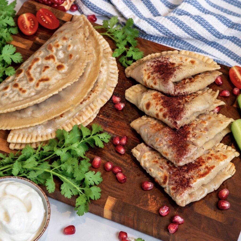 Meat-Stuffed Flatbread (Azerbaijani Qutab) served on a wooden board with sumac and yoghurt