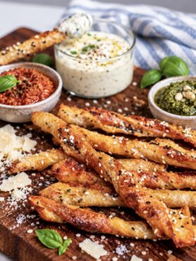 Pesto Parmesan Rice Paper Twists served on a wooden board with dipping sauce