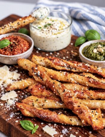Pesto Parmesan Rice Paper Twists served on a wooden board with dipping sauce