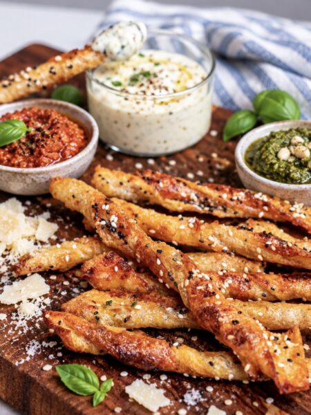 Pesto Parmesan Rice Paper Twists served on a wooden board with dipping sauce