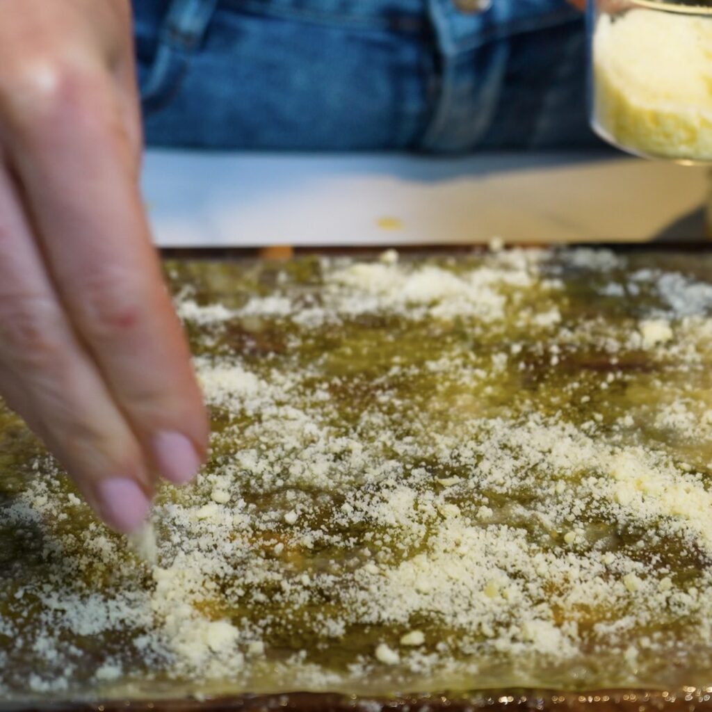 Sprinkling grated Parmesan over rice paper for Pesto Parmesan Rice Paper Twists