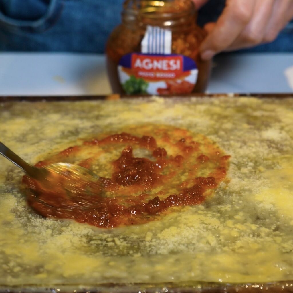 Spreading sun-dried tomato pesto over rice paper for Pesto Parmesan Rice Paper Twists