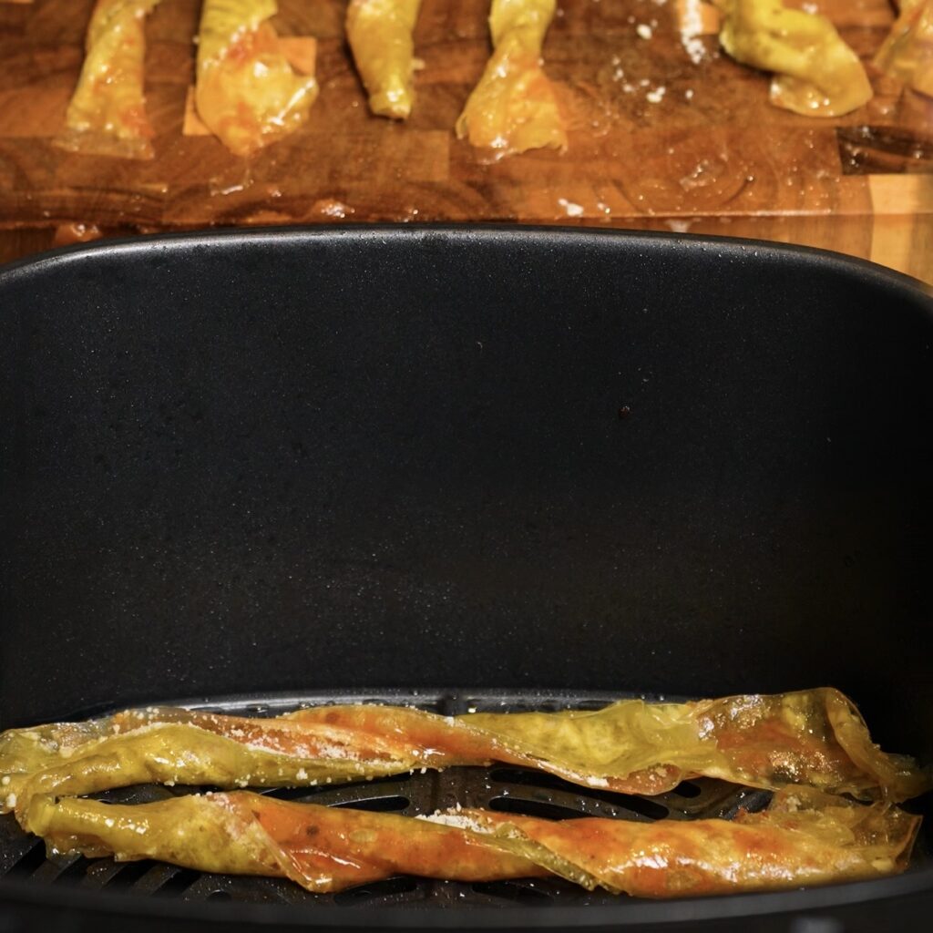 Pesto Parmesan Rice Paper Twists arranged in the air fryer basket before cooking
