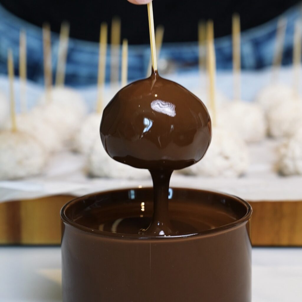 Dipping frozen Banana Coconut Truffles into melted chocolate
