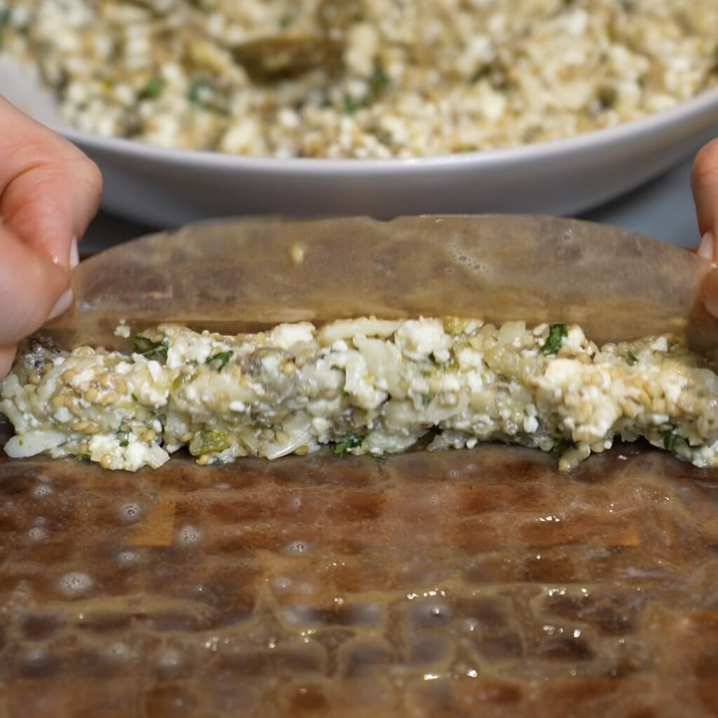 Rolling rice paper around the aubergine and feta filling