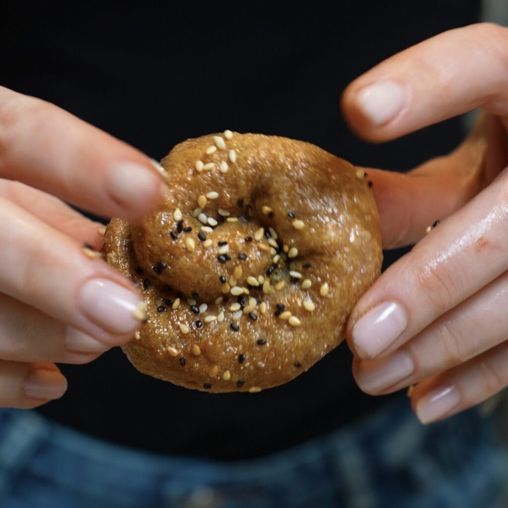 Hands holding a freshly air-fried Aubergine & Feta Rice Paper Roll