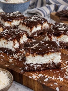 Slices of 5-Minute No-Bake Coconut Cheesecake served on a wooden board.