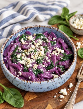 Purple sweet potato gnocchi with spinach and feta served on a plate.
