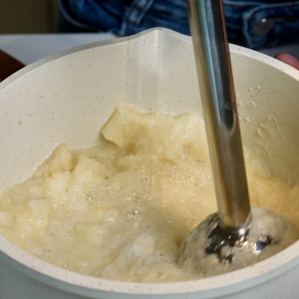Blending peeled and cubed pears with an immersion blender until smooth for Pear Cloud Cubes with Cinnamon Filling.