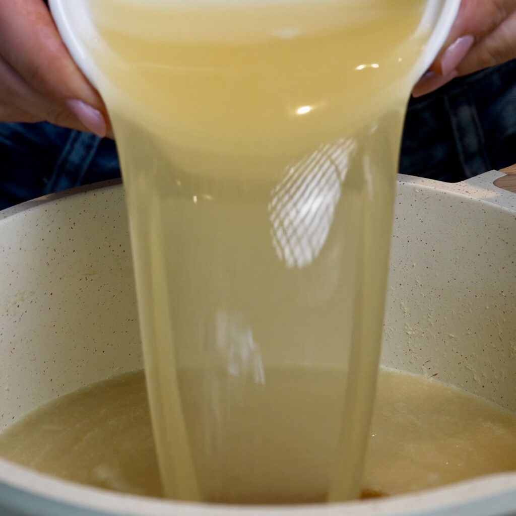 Pouring melted gelatine into smooth pear purée to prepare the base for Pear Cloud Cubes with Cinnamon Filling.