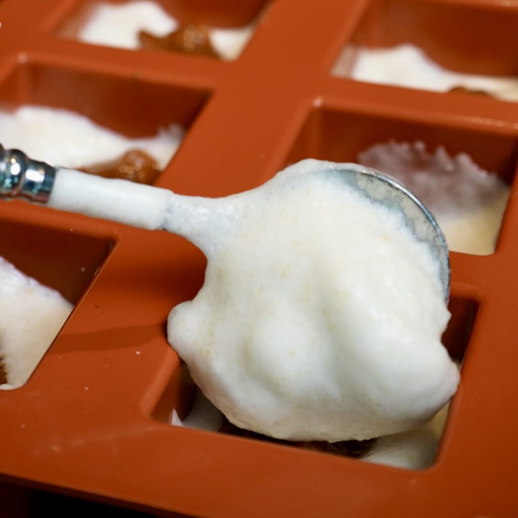 Covering the cinnamon-spiced pear filling with more fluffy pear mixture in a silicone mould to make Pear Cloud Cubes.