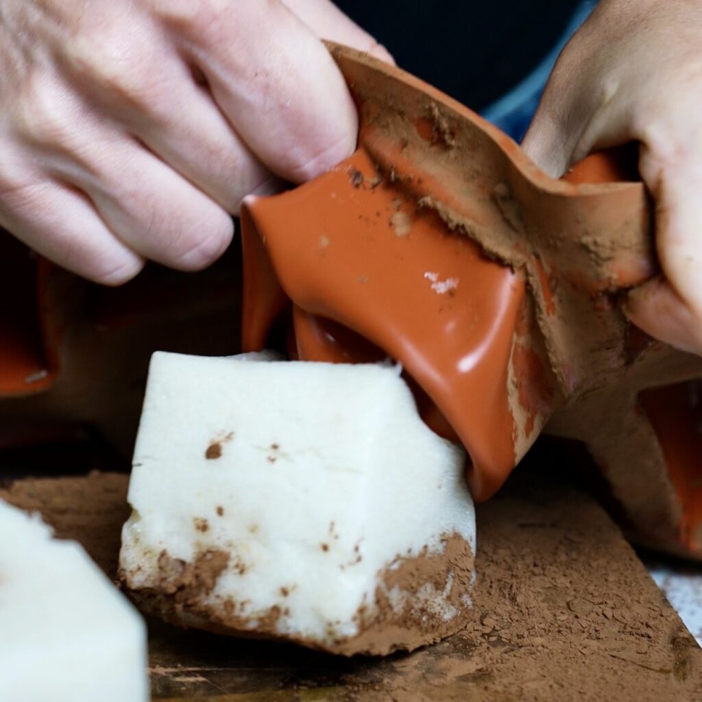 Gently removing a set Pear Cloud Cube from a silicone mould after chilling, revealing its soft, fluffy texture.